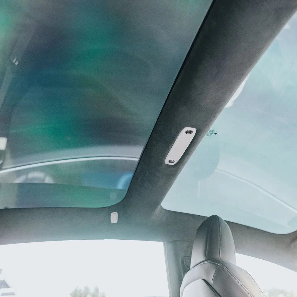 Tesla cabin looking up at a two-pane glass roof with dark charcoal suede / Alcantara-style headliner.