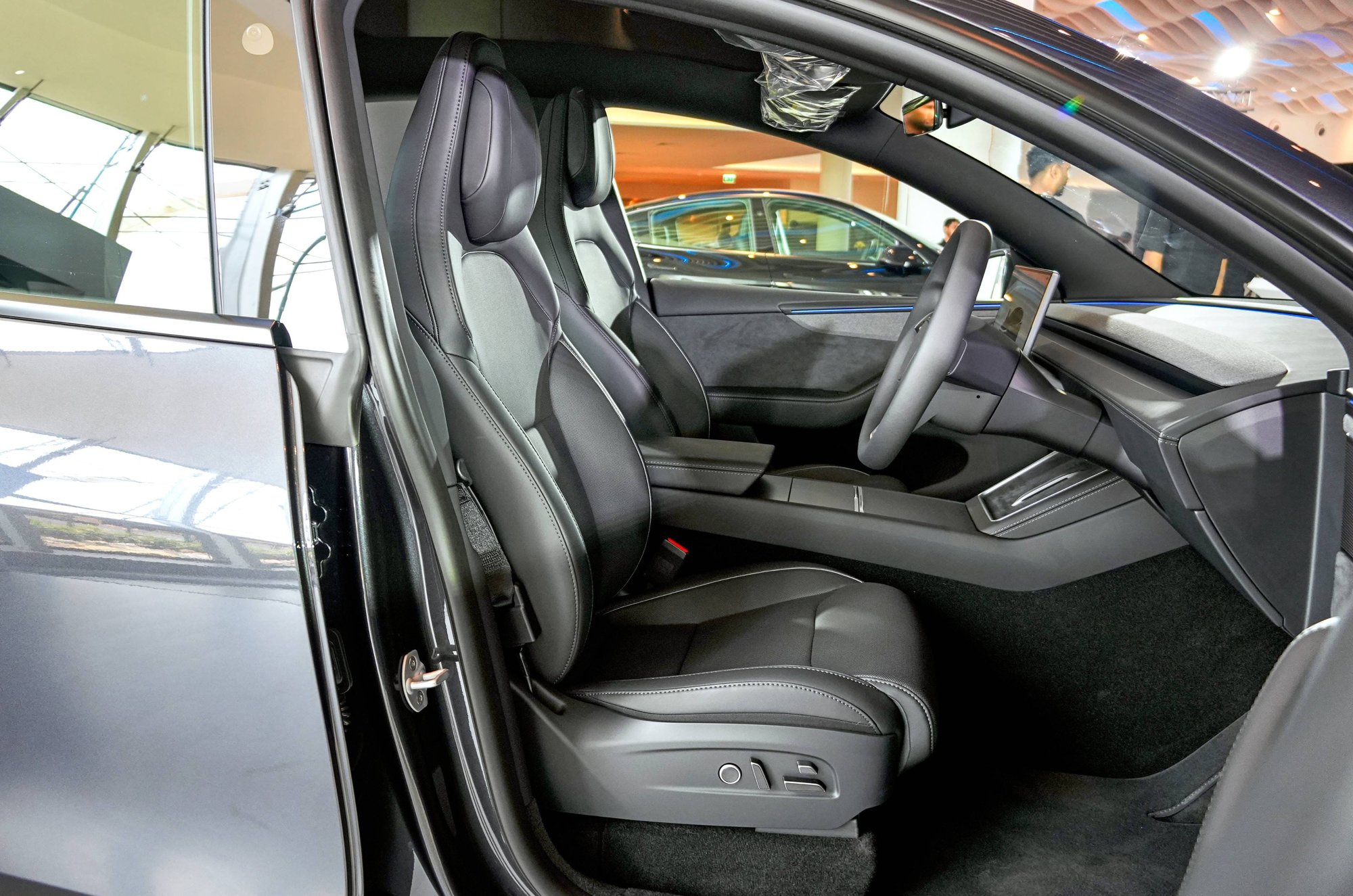Tesla Model Y L black cabin viewed through an open front door, seats and dash in dark finish.
