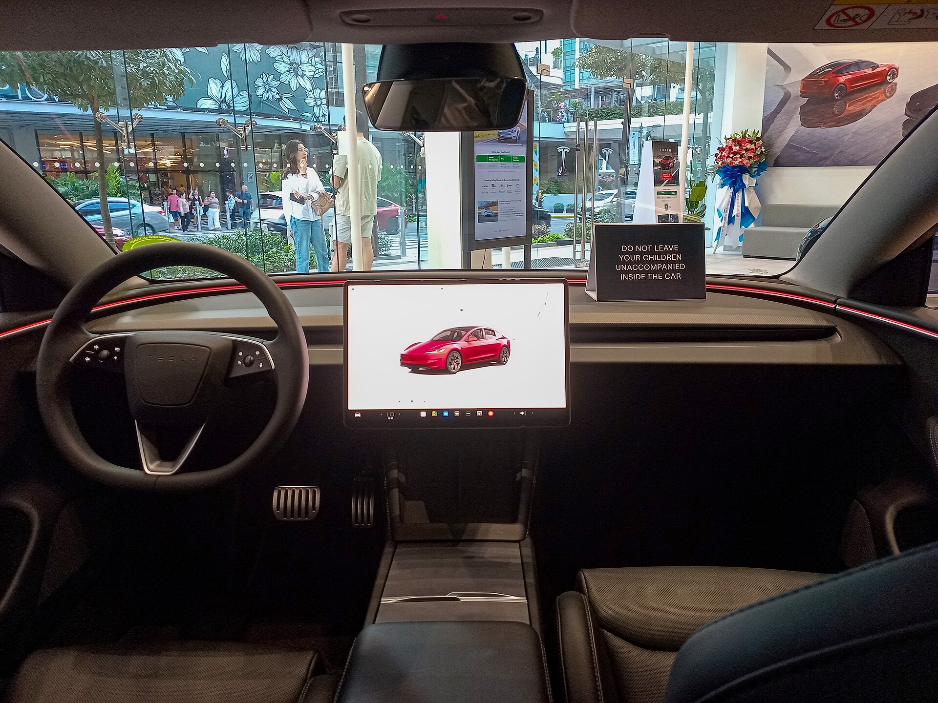 Tesla Model 3 Performance Highland showroom cabin with black seats, crimson ambient dash light, and center screen.