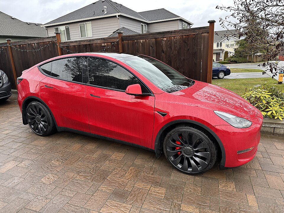 Red Tesla Model Y, front three-quarter exterior.