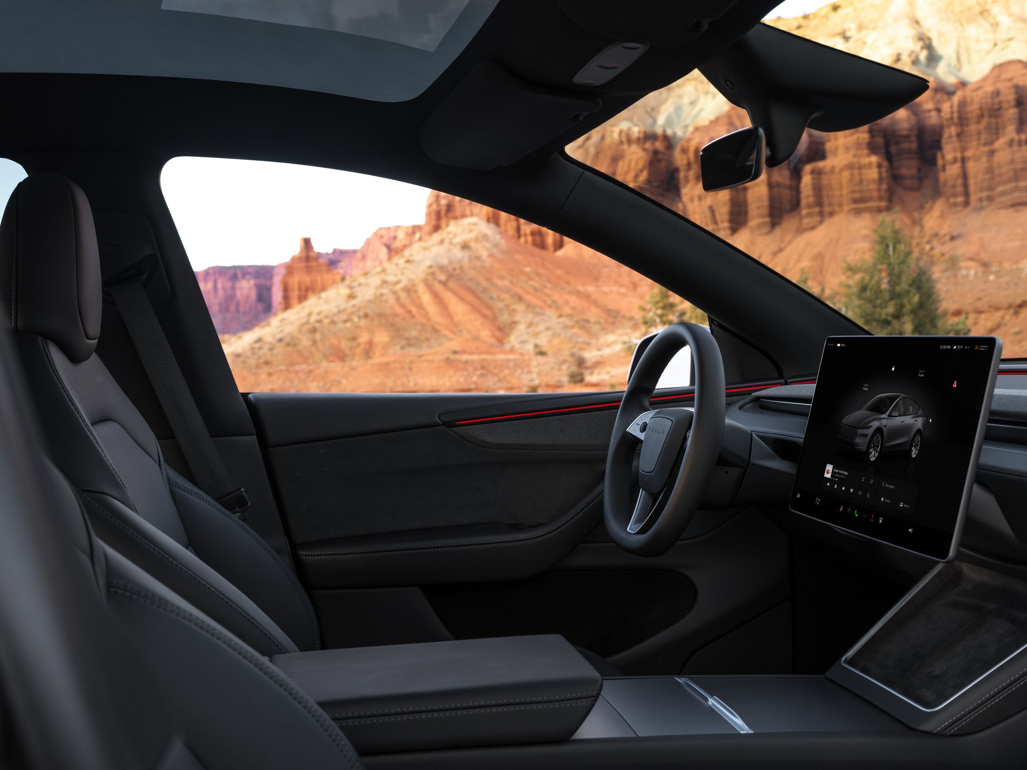 Tesla cabin with black seats, dark pillars, and red ambient lighting along the dash.